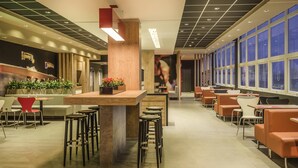 A modern restaurant with a bar area, seating, and large windows. - ibis Porto Alegre Assis Brasil (Porto Alegre)