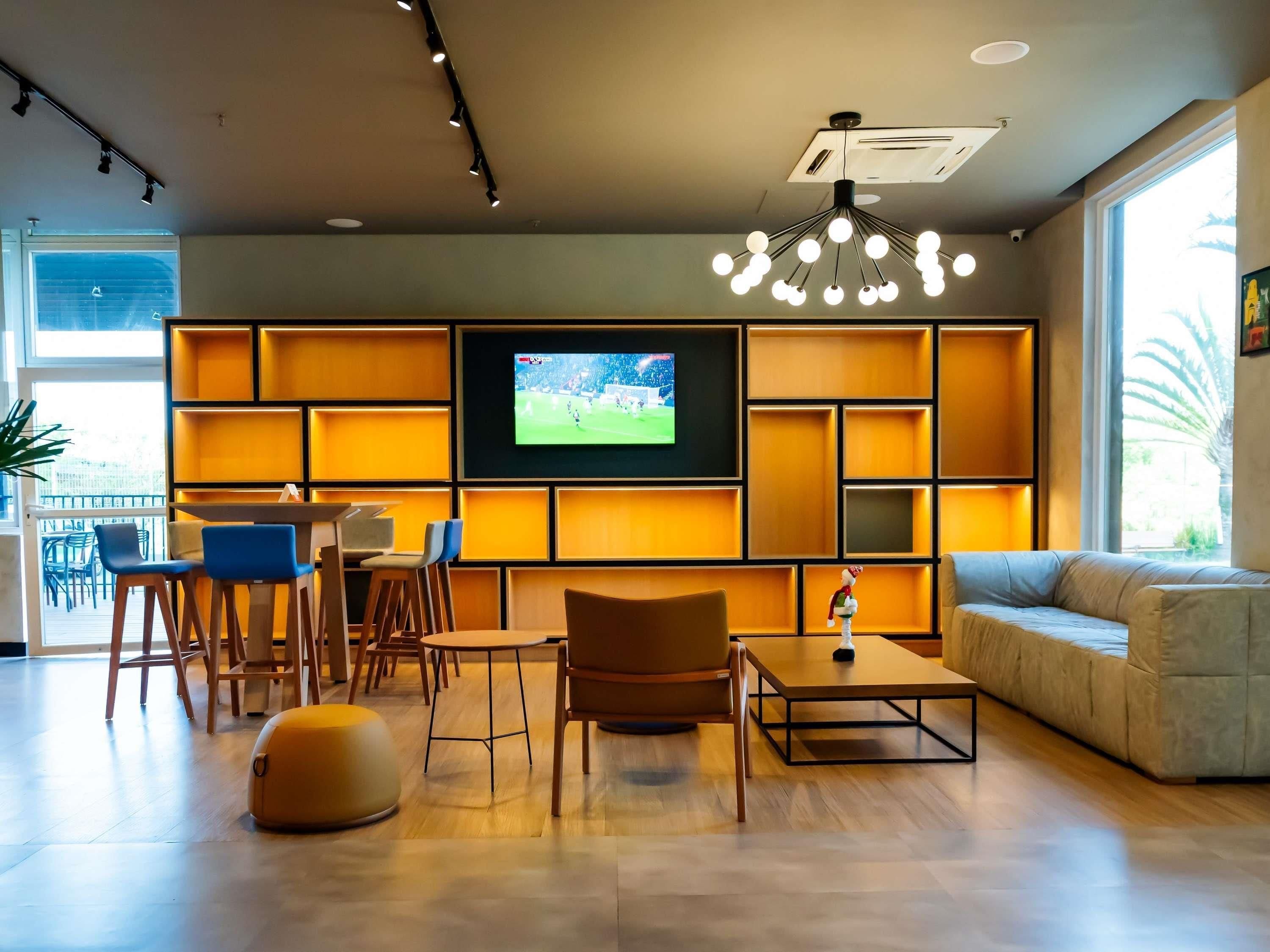 Un salon moderne doté d’un téléviseur à écran plat, de meubles en bois et d’une grande fenêtre.