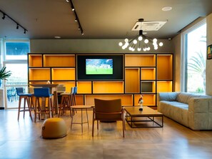 Una sala de estar moderna con un televisor de pantalla plana, muebles de madera y un ventanal grande.