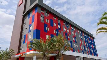 Um hotel com várias andares e fachada moderna, combinando cores vermelho, azul e cinza.