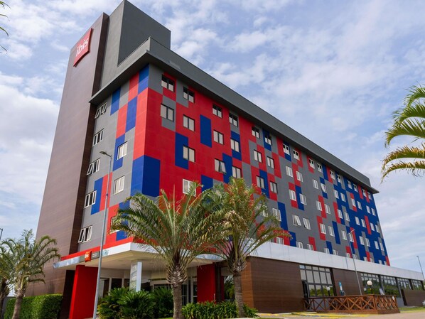 Un hôtel à plusieurs étages doté d’une façade moderne, caractérisée par un mélange de couleurs rouge, bleu et gris.