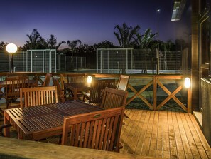 Terraza exterior con mobiliario de madera y valla de metal.