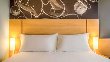 Una habitación de hotel con una cama grande, dos lámparas de noche y una pared decorada con arte abstracto.