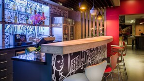A bar area with a counter, chairs, and a wall with a mural. - ibis Porto Alegre Assis Brasil (Porto Alegre)