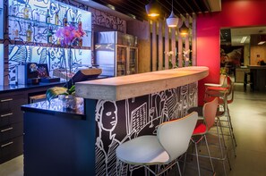 A bar area with a counter, chairs, and a wall with a mural. - ibis Porto Alegre Assis Brasil (Porto Alegre)
