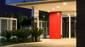 A modern gas station with a red and white color scheme, featuring a well-lit entrance and a clean, landscaped area with palm trees. - ibis Porto Alegre Assis Brasil (Porto Alegre)