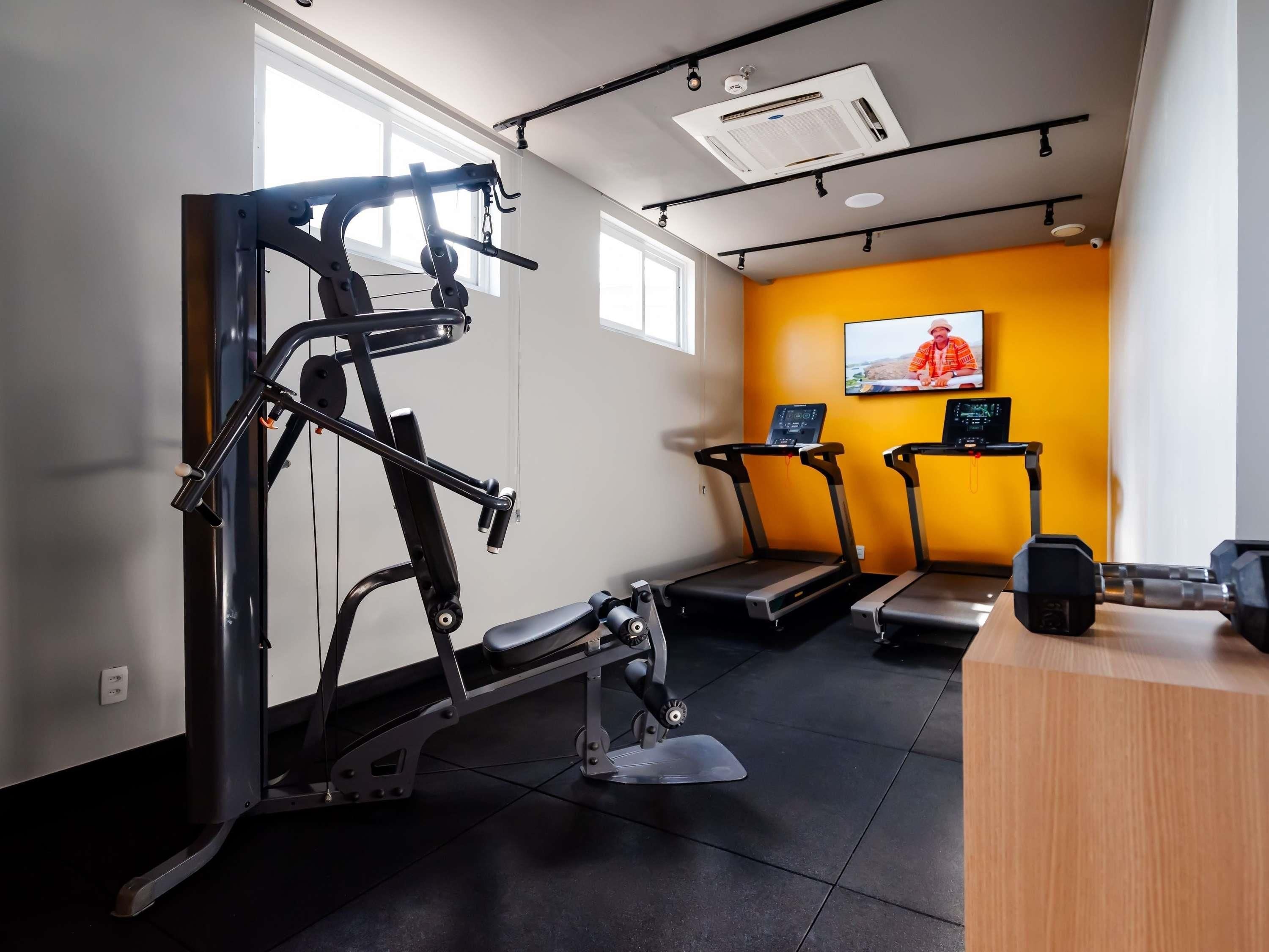 A gym with exercise equipment, treadmills, and a wooden desk.