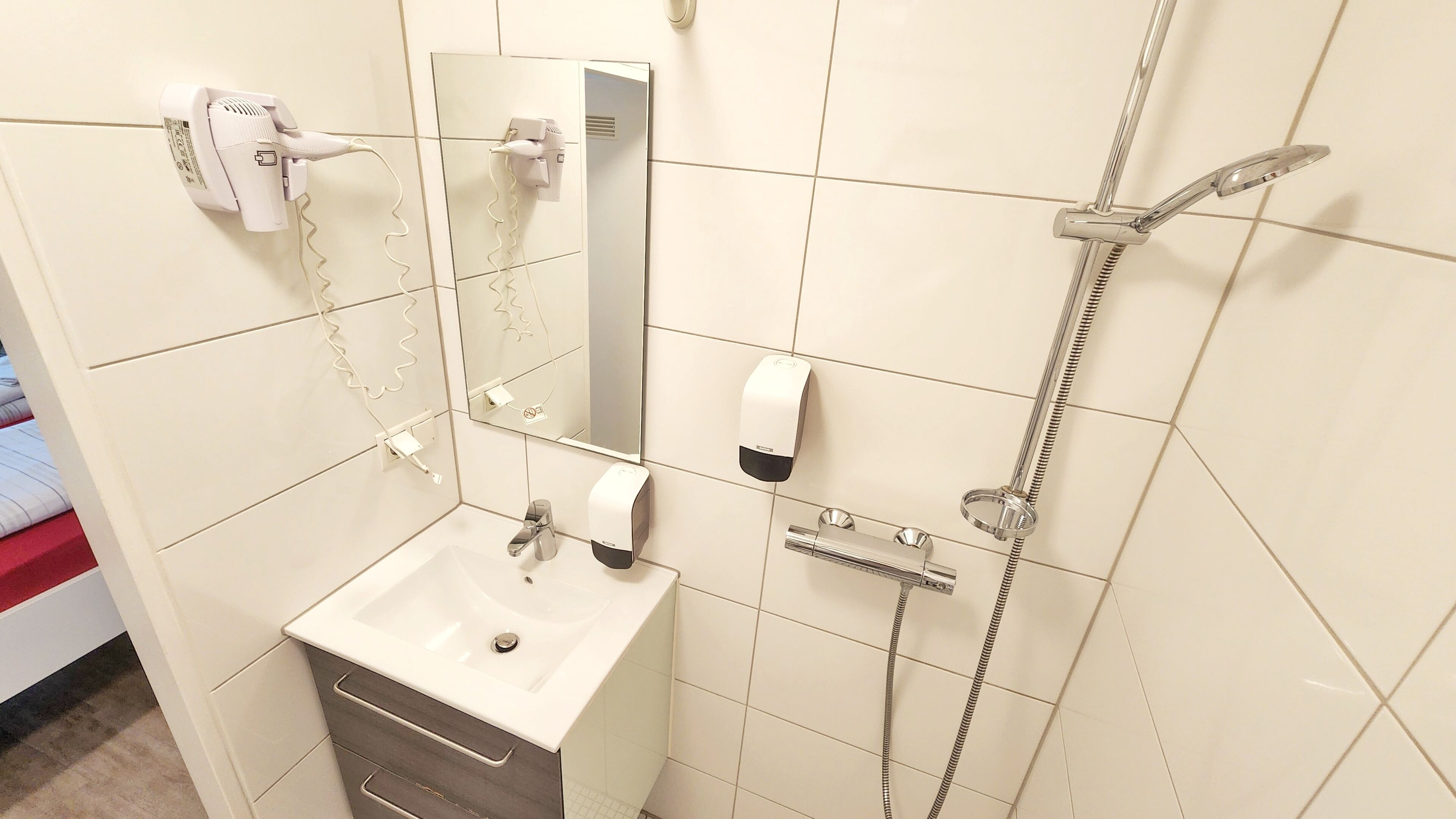 A bathroom with a sink, mirror, towel rack, and shower.