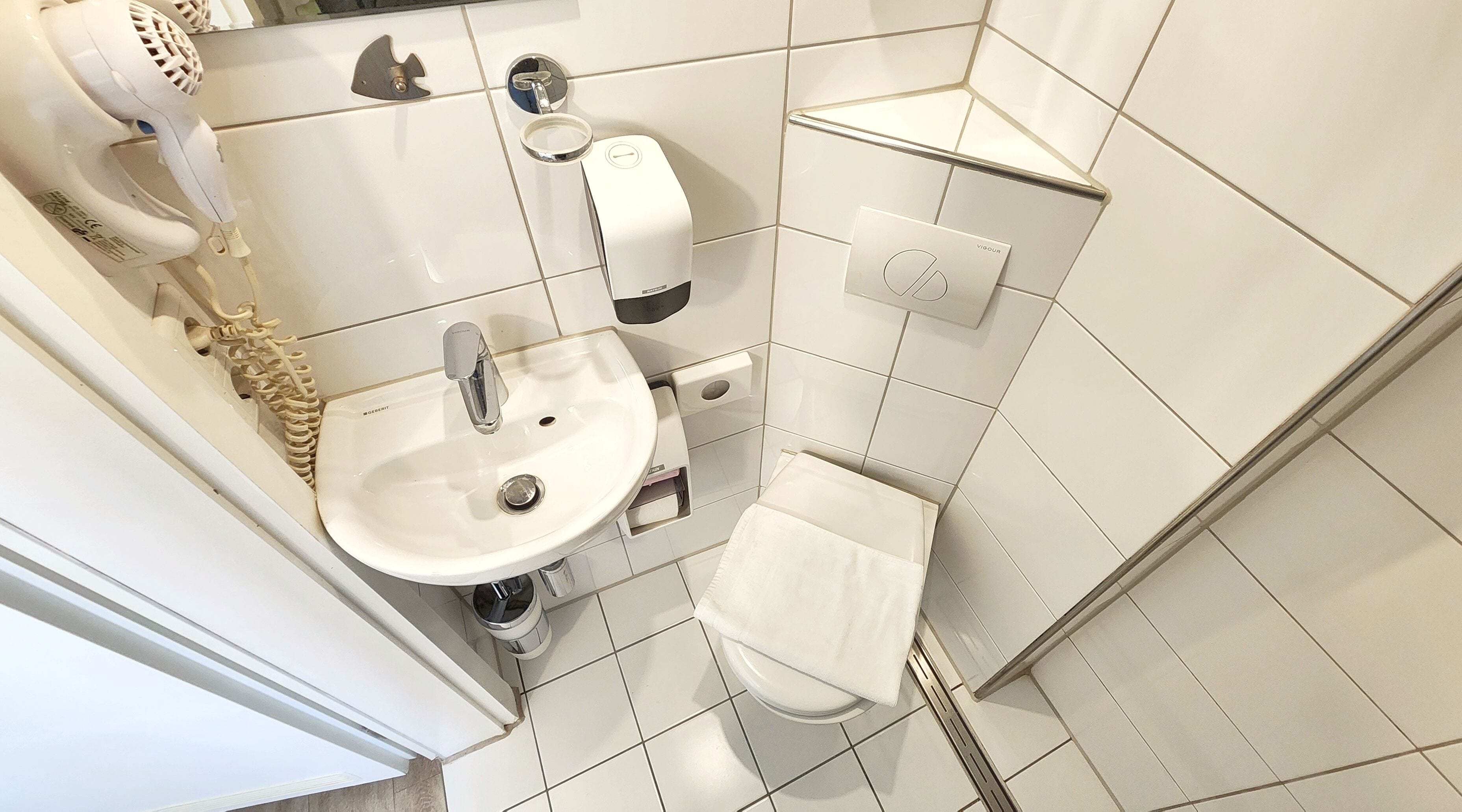 A bathroom with a sink, toilet, and hairdryer.