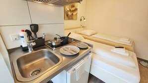 A compact kitchenette with a sink, stove, and dining set. - Aparthotel Marion Weber (Bremen)
