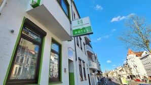A hotel with a green and white facade, a visible window with a reflection, and a sign indicating the hotel name. - Aparthotel Marion Weber (Bremen)