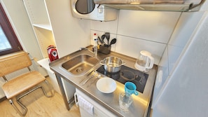 A compact kitchenette with a stainless steel sink, a stove, a coffee maker, and a microwave. - Aparthotel Marion Weber (Bremen)