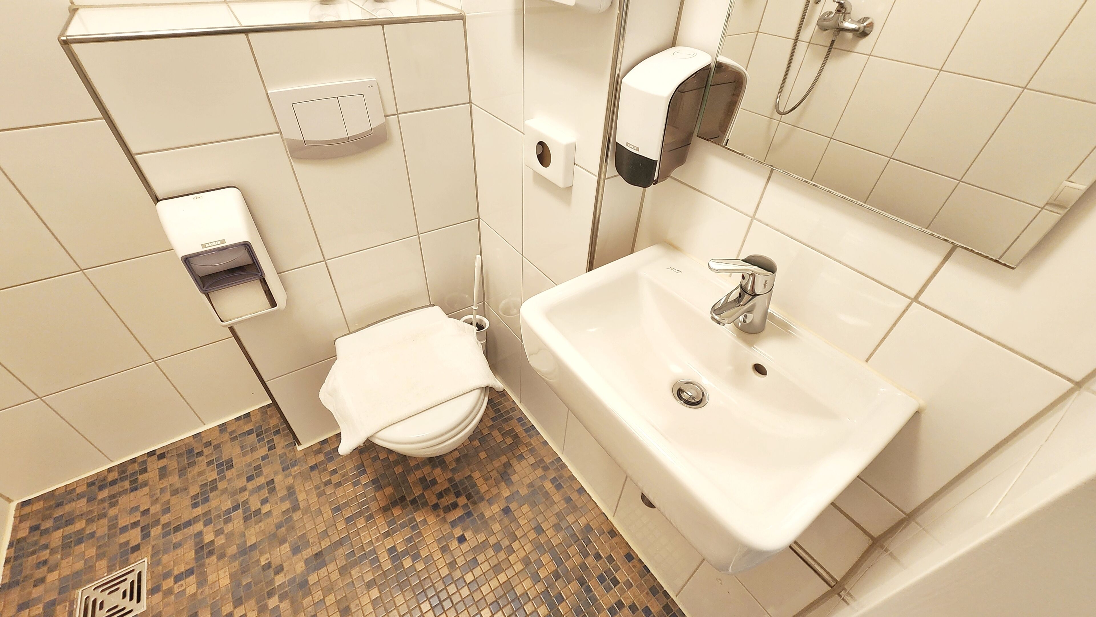 Un baño con inodoro, lavamanos y secamanos.