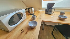 A compact kitchen with a washing machine, a kettle, a coffee maker, and a dining table. - Aparthotel Marion Weber (Bremen)