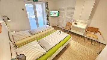 A hotel room with two beds, a television, a chair, and a desk.
