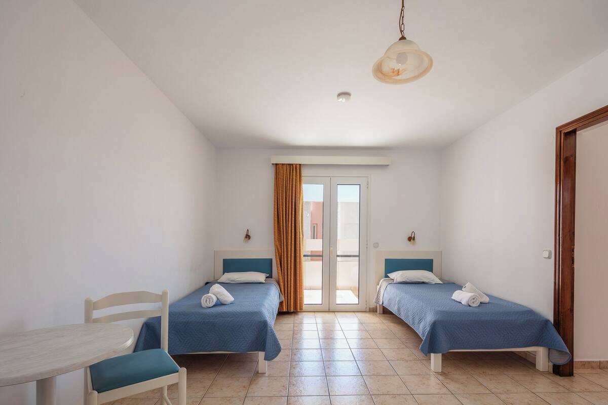 Une chambre avec deux lits, une table et une chaise.