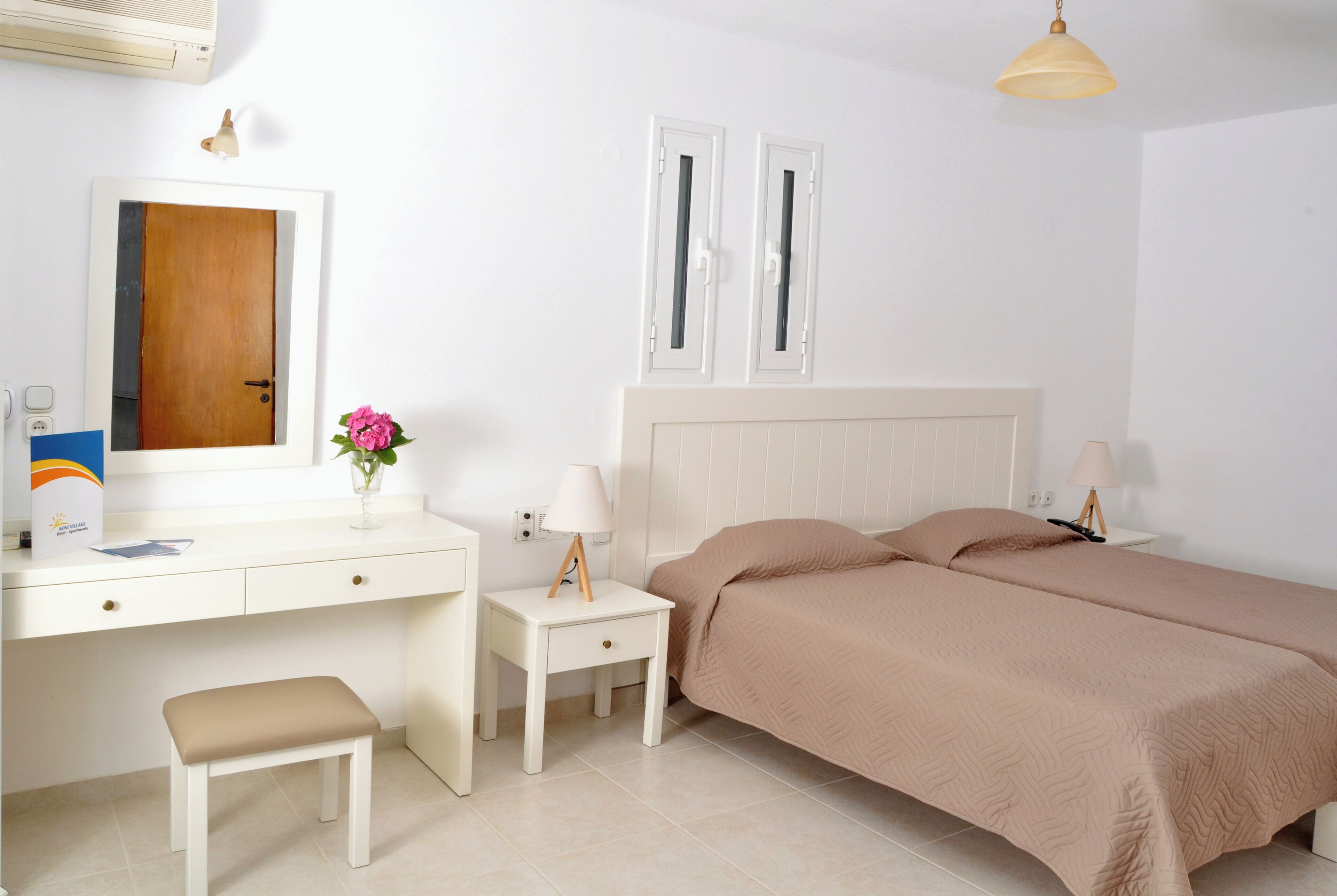 A bedroom with a bed, bedside tables, a desk, a chair, a mirror, and a window.