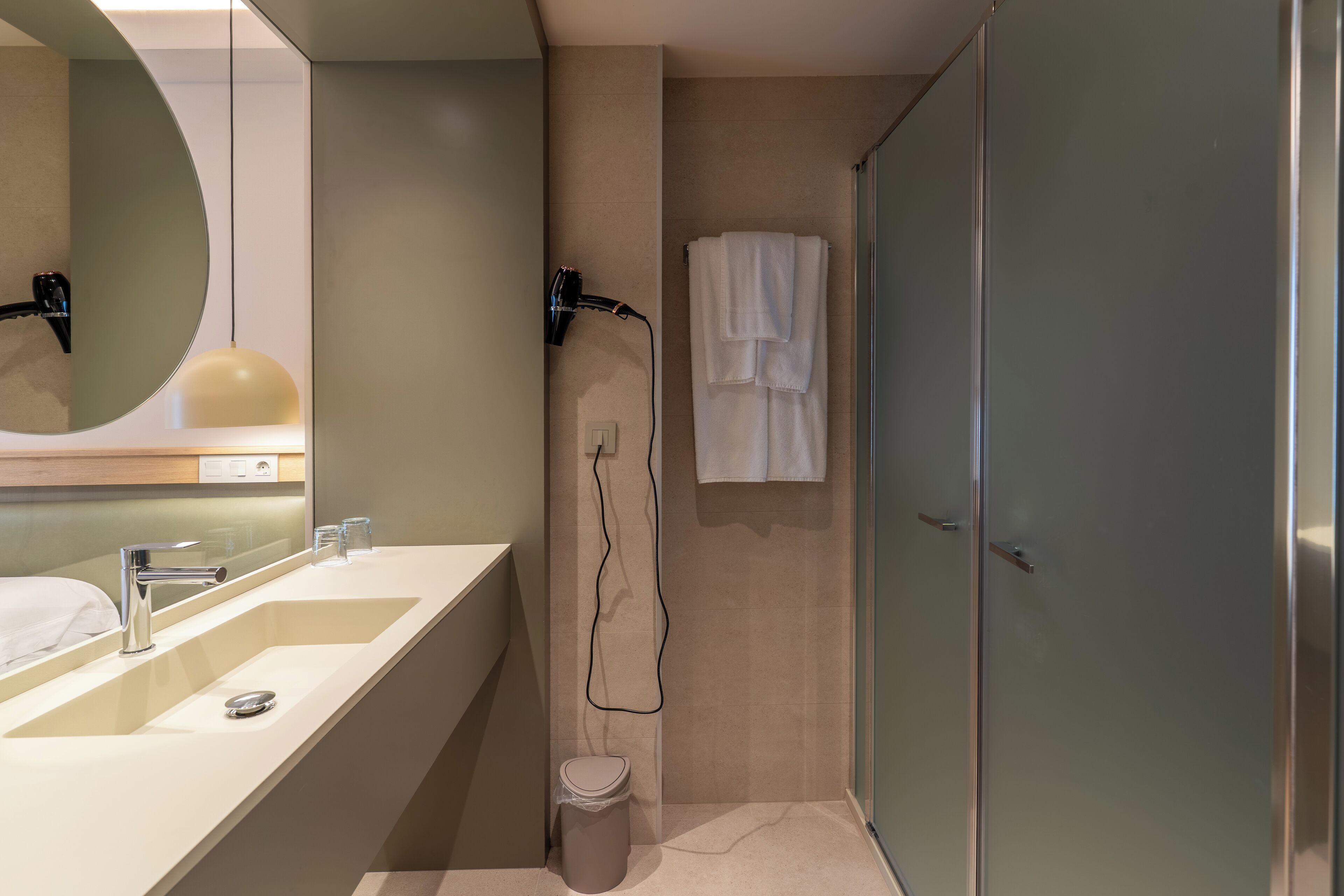Un baño moderno con un espejo grande, dos lavamanos, una ducha y un inodoro.