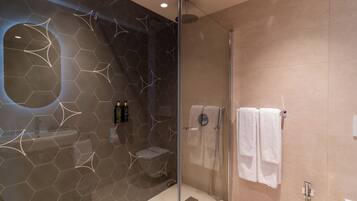 A modern bathroom with a glass-enclosed shower, a sink with a mirror, and a towel rack.