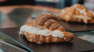 Una vitrina de pastelería con varios productos horneados, incluyendo un croissant y un sándwich con crema de chocolate.