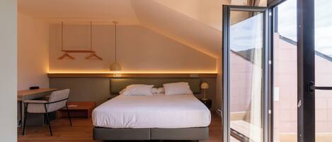 A modern bedroom with a large bed, a desk, and a chair.