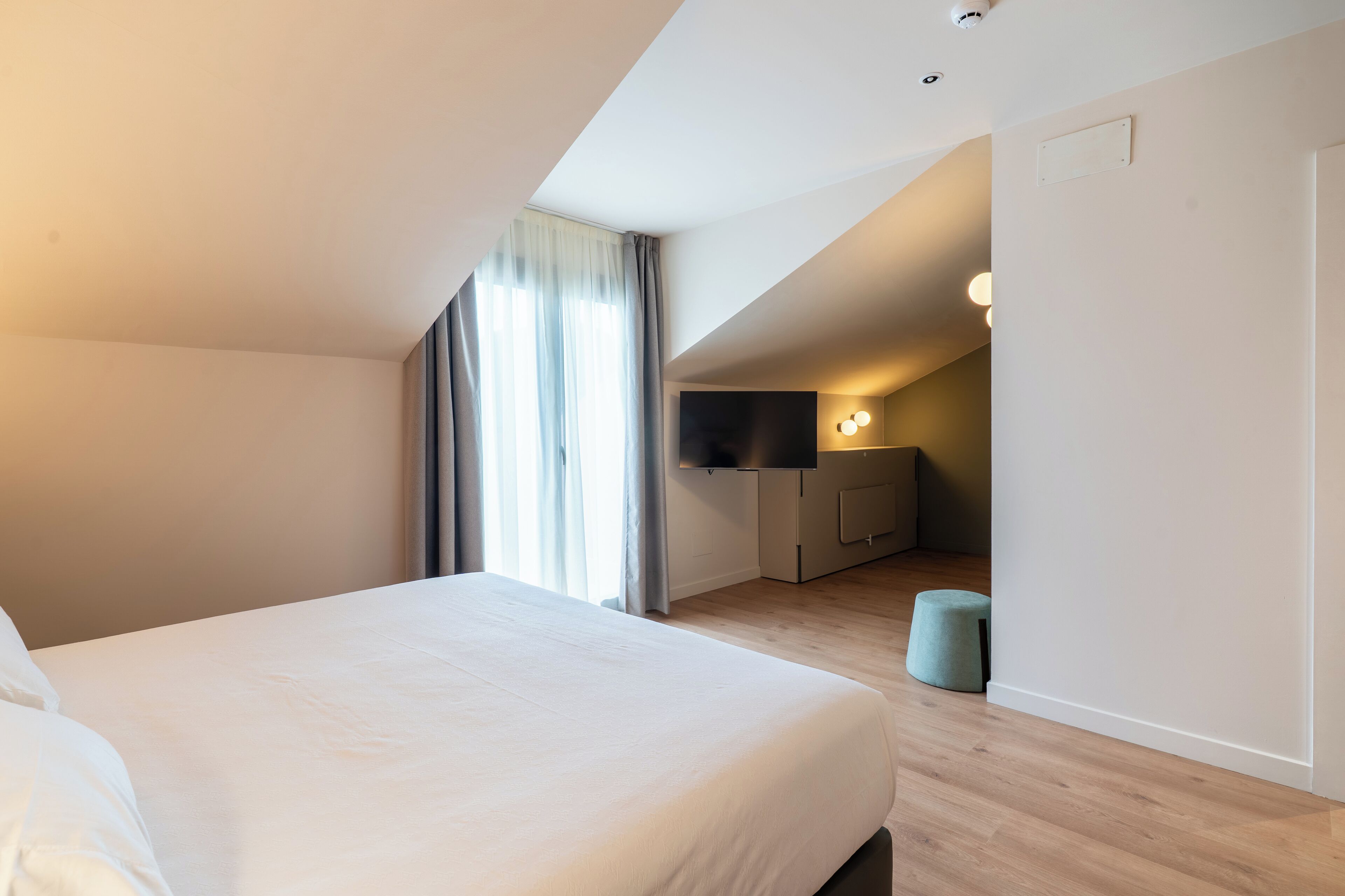 A modern hotel room with a large bed, a desk, and a TV.