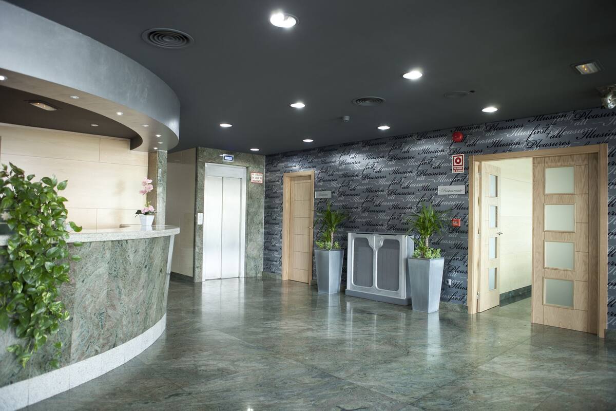 A modern reception area with a marble counter, potted plants, and a stone wall.