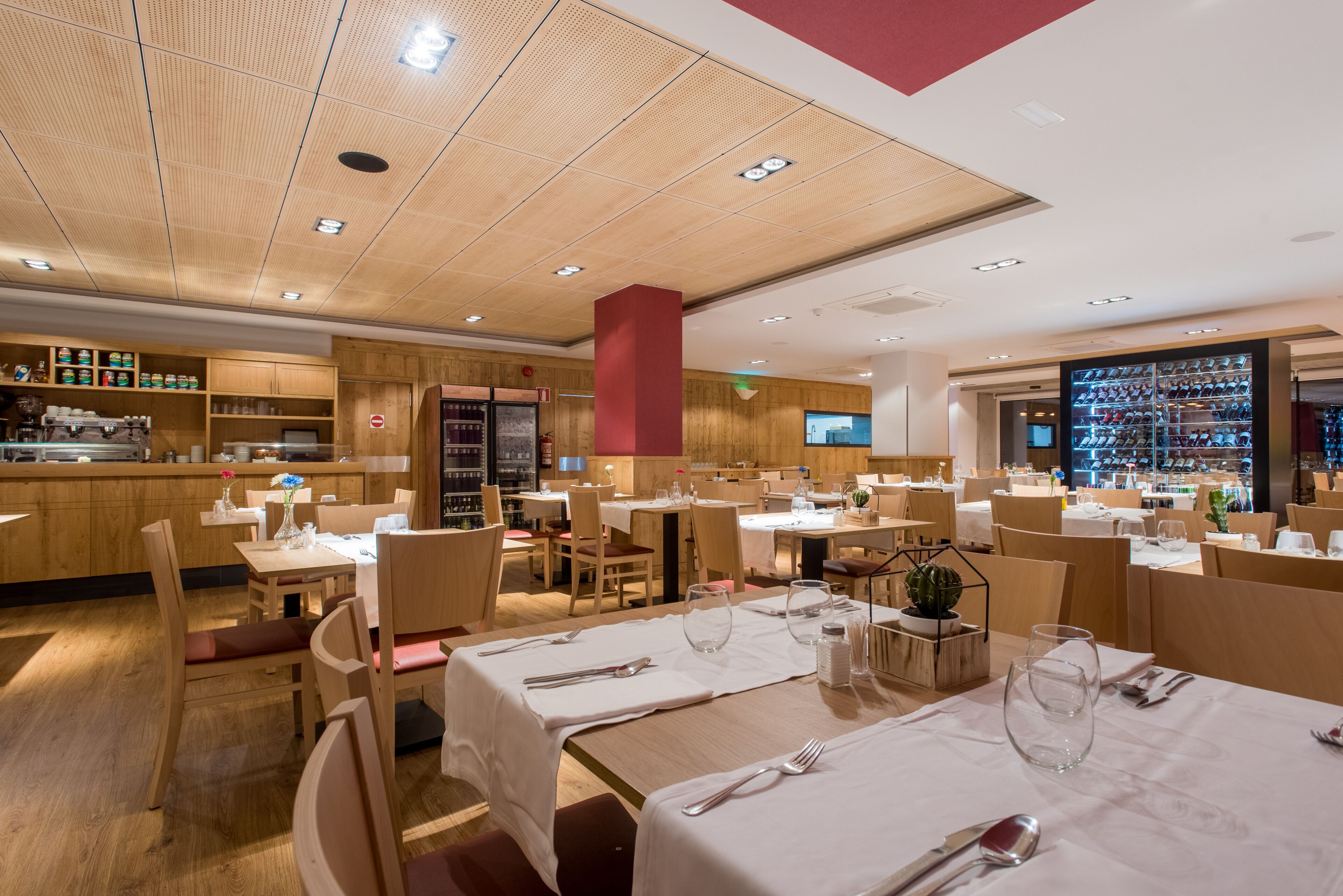 Un restaurante con interiores de madera, varias mesas de comedor con manteles blancos y diversas opciones de asientos.