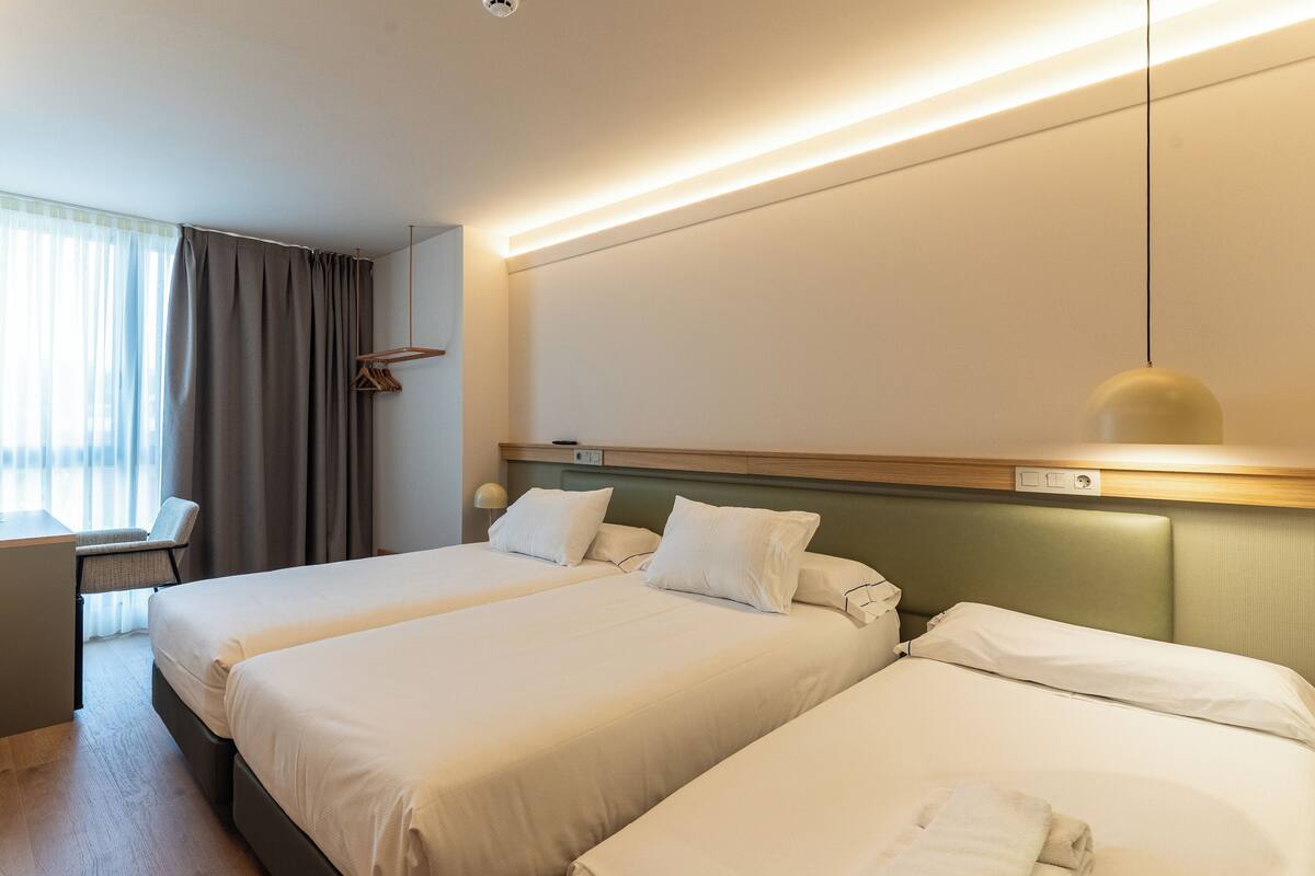 A hotel room with two beds, a desk, and a chair.