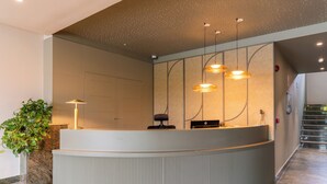 Un espace d’accueil doté d’un comptoir incurvé, d’une plante en pot et d’un éclairage suspendu.