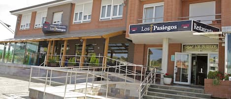 Hotel 'Los Pasiegos' con un letrero, una escalera que lleva a la entrada y un área exterior cubierta con plantas.