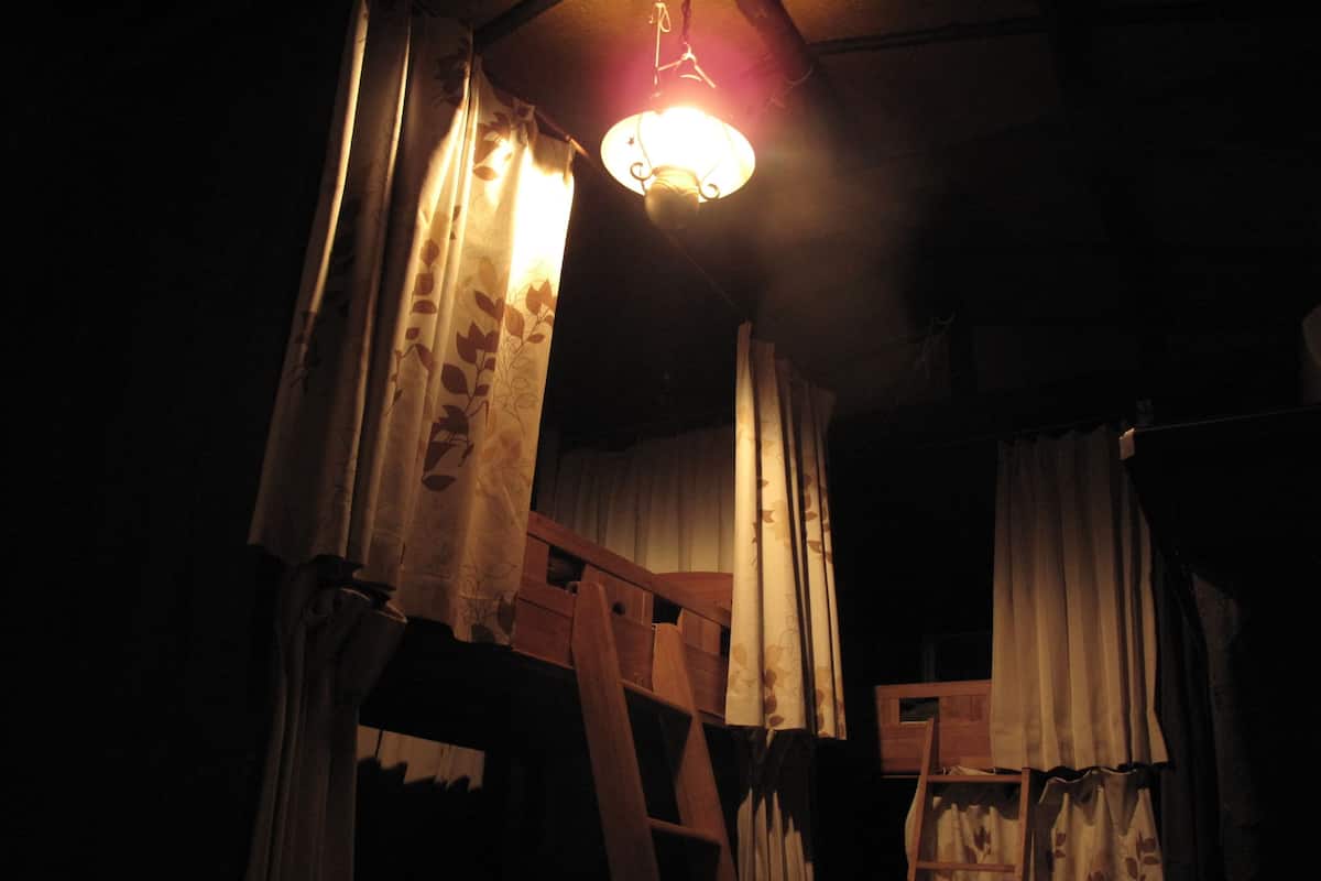 A dimly lit room with a wooden ladder and curtains.