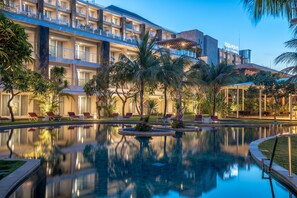 A hotel with a pool, palm trees, and a well-lit exterior. - Four Points by Sheraton Bali, Ungasan (Ungasan)