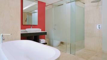 A modern bathroom with a freestanding bathtub, a glass-enclosed shower, and a red accent wall.