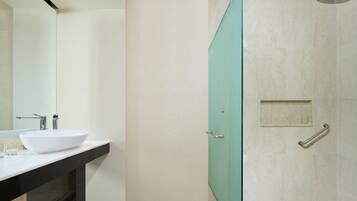 A modern bathroom with a white sink, a glass shower enclosure, and a mirror.