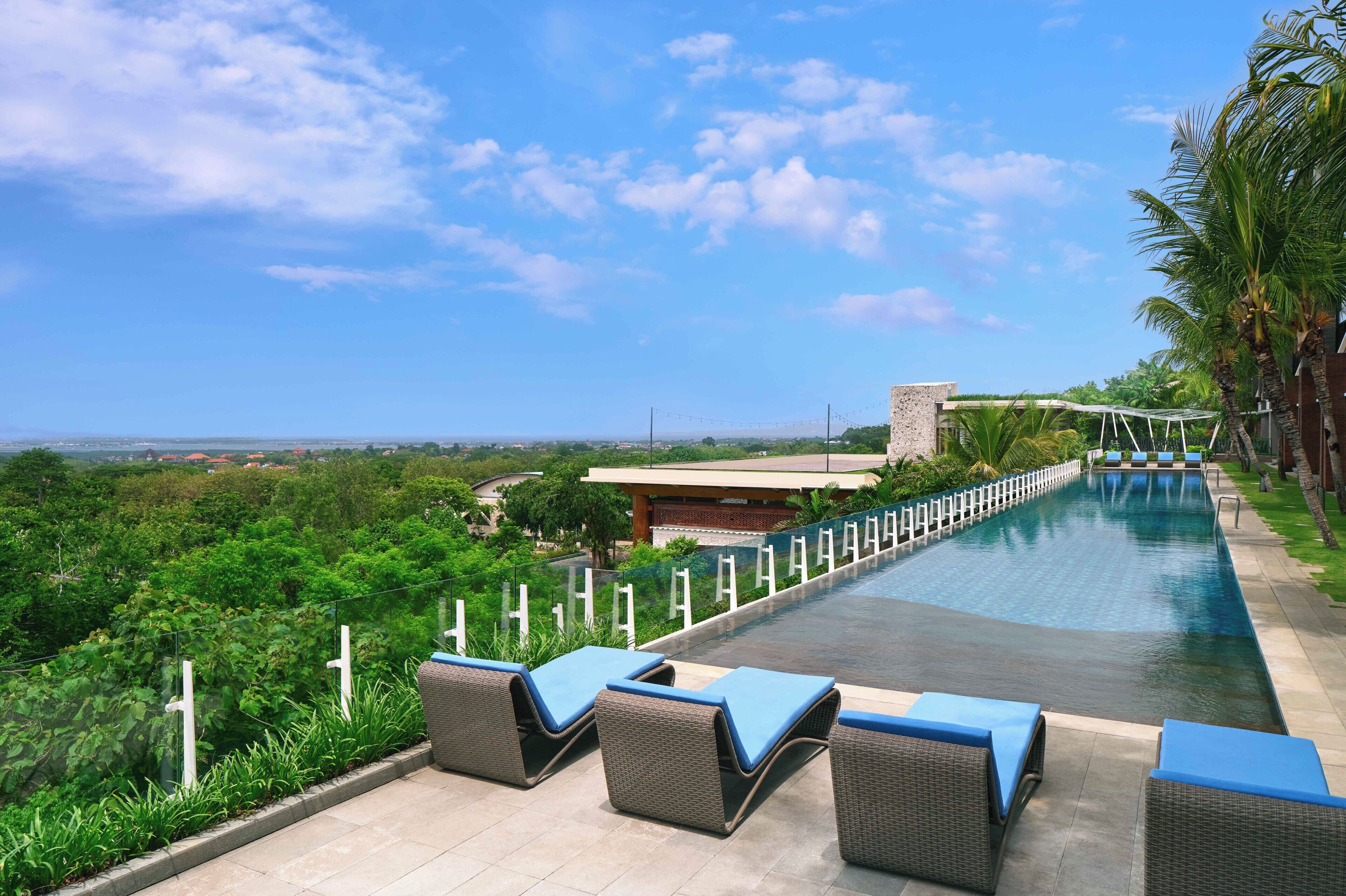 Una piscina con sillones de descanso, cielo despejado y vistas al paisaje.