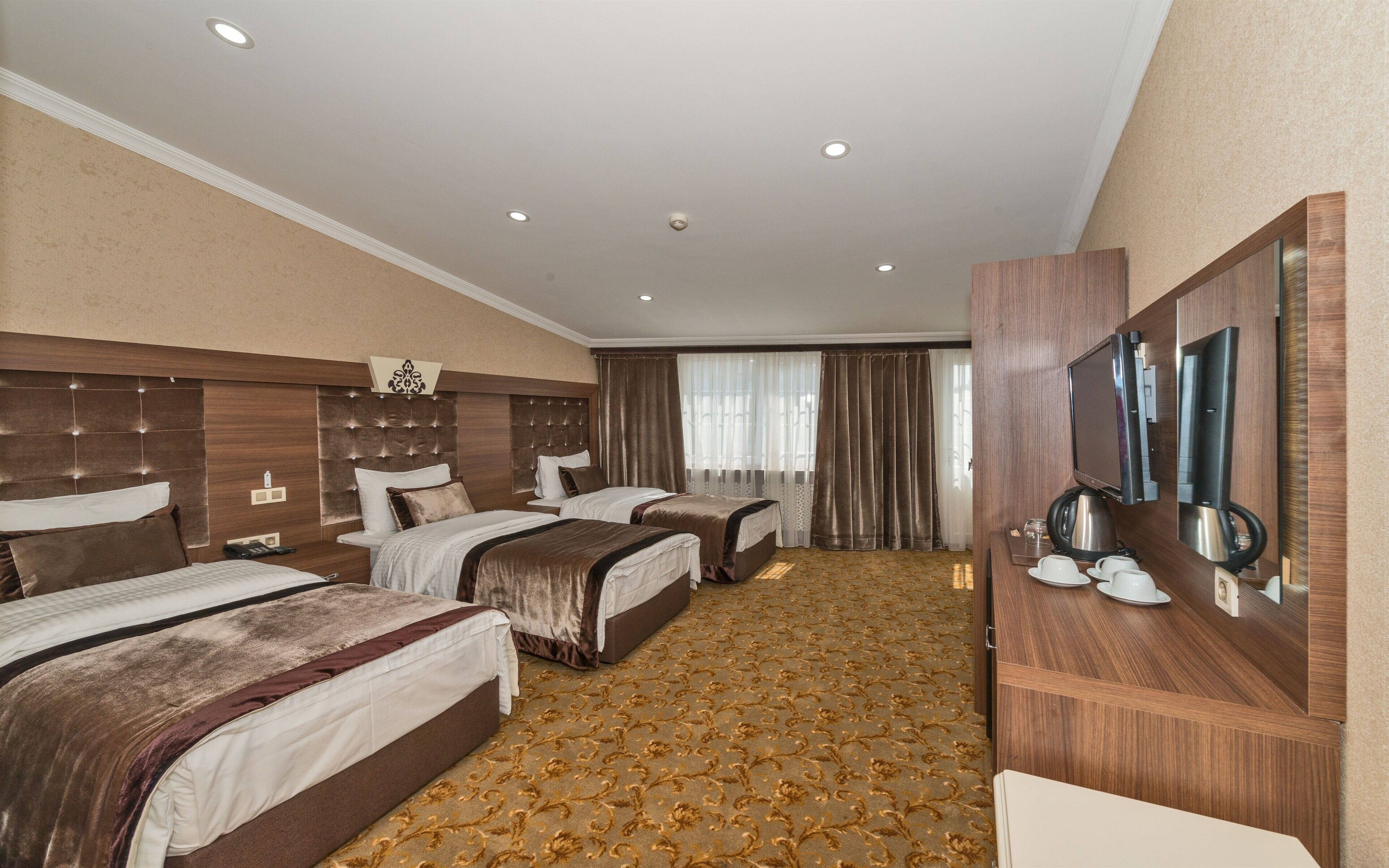 A hotel room with two beds, a large mirror, a television, and a coffee maker.