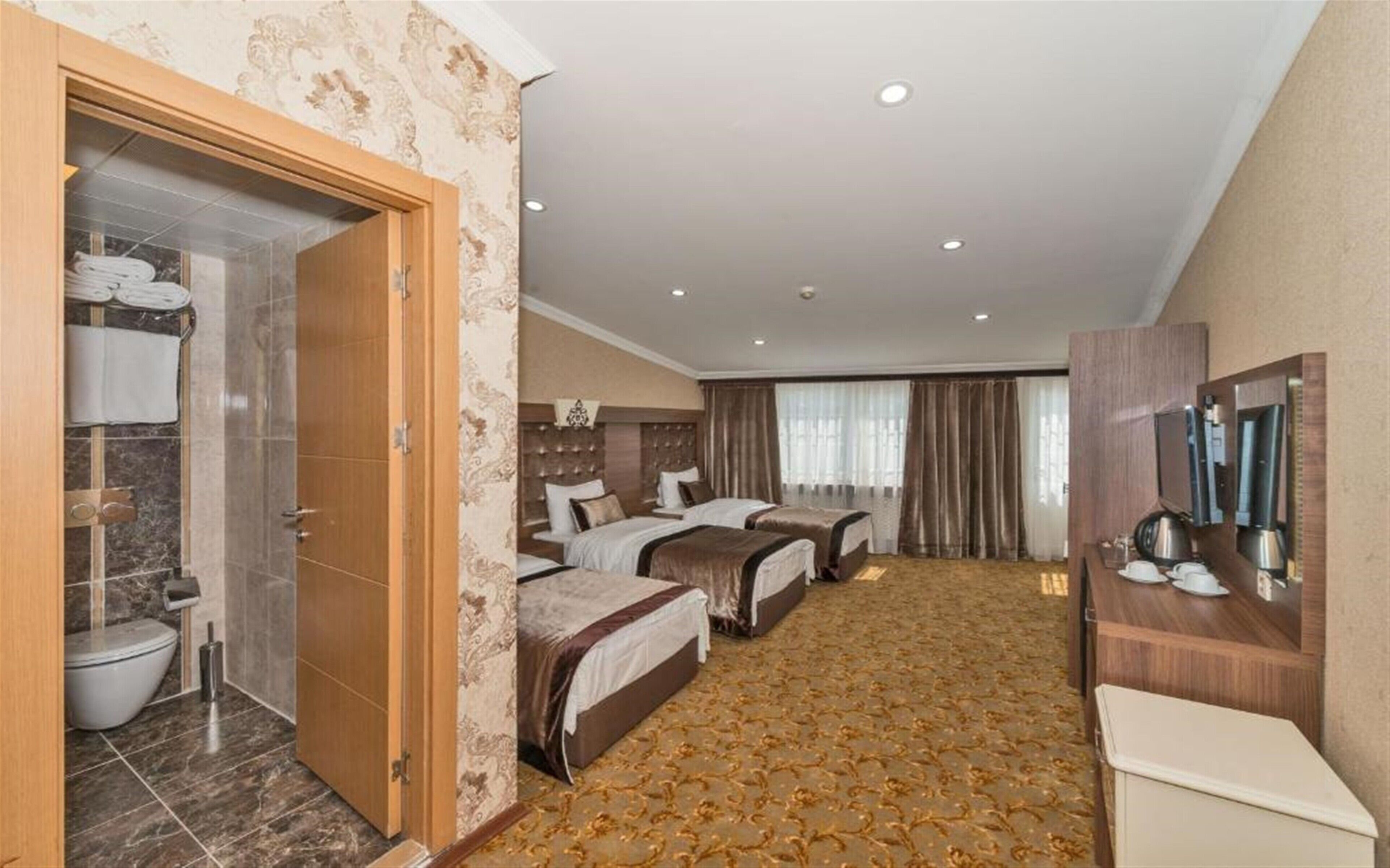 A hotel room with two beds, a bathroom with a toilet, and a minibar.