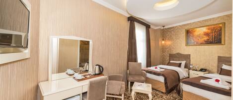 A hotel room with a desk, chair, two beds, a mirror, a painting, and a patterned carpet.