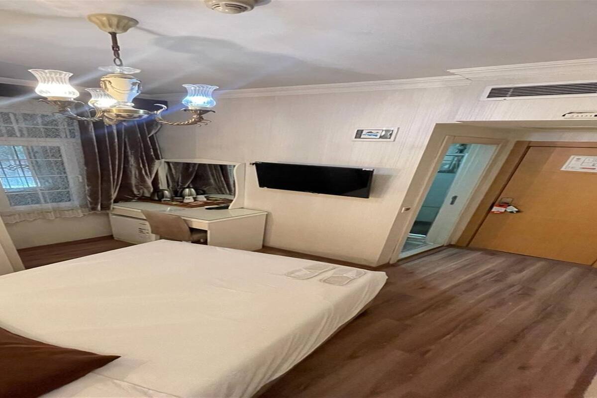 Habitación de hotel con cama, escritorio, silla y televisor de pantalla plana montado en la pared.