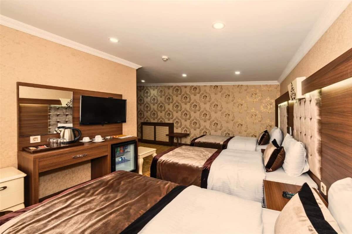 Una habitación de hotel con dos camas, televisión, escritorio con hervidor y una pequeña mesa.