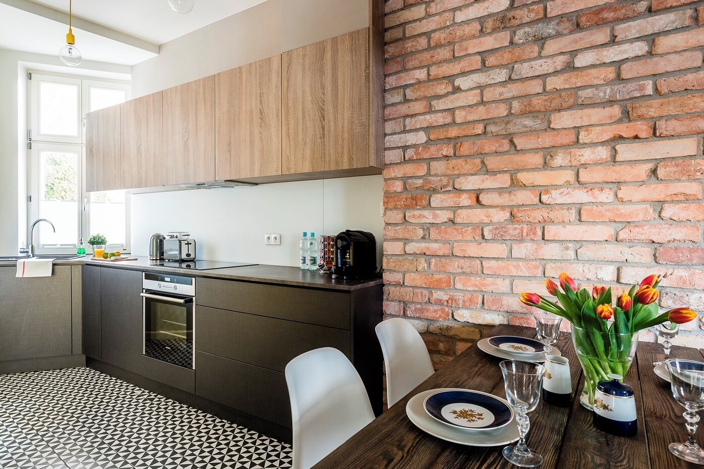 Eine moderne Küche mit Holzausziehtisch, integriertem Backofen und Backsteinwand.