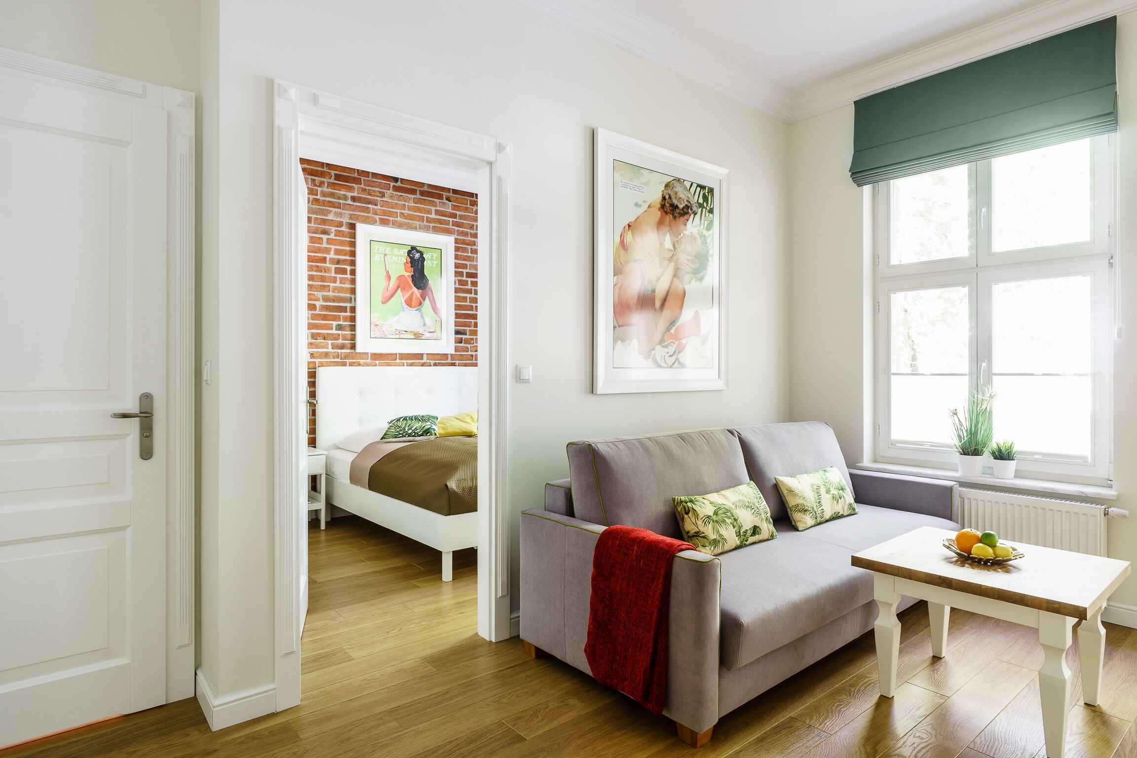 A modern living room with a grey sofa, a wooden coffee table, and a brick wall.