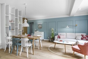 Una sala de estar moderna con comedor, que incluye un sofá blanco, una mesa redonda de centro y una mesa de comedor con sillas.