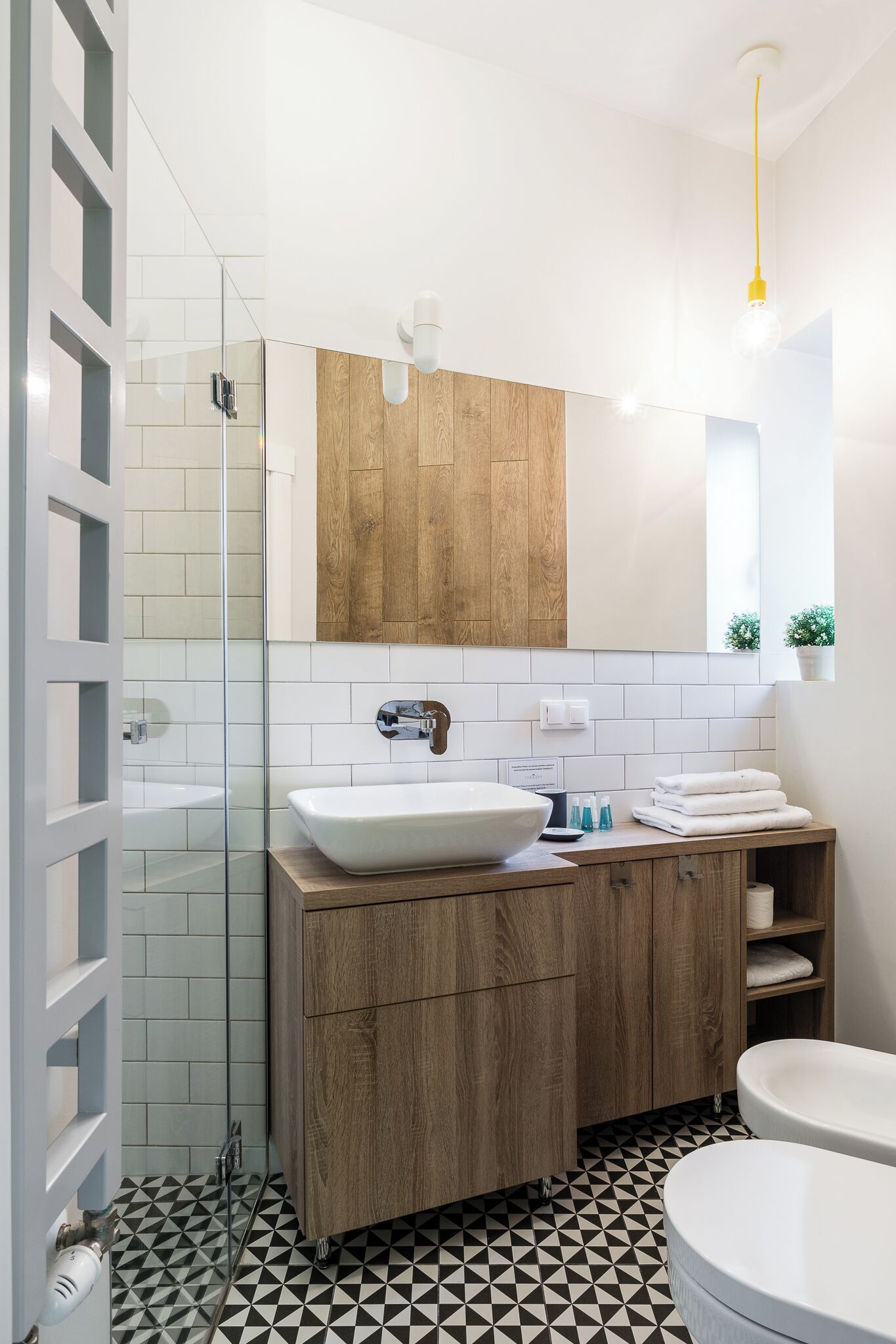 Ein modernes Badezimmer mit Duschkabine aus Glas, einem Holzlagerflansch mit weißem Waschbecken und einem großen Spiegel darüber.