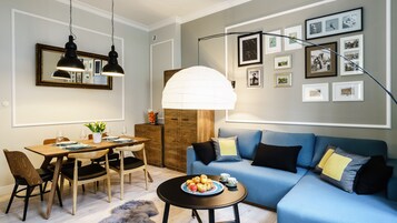 Una sala moderna con comedor, un sofá azul y una mesa de comedor de madera.