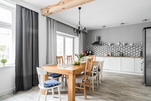 Una cocina moderna con armarios blancos, una mesa de comedor de madera y una araña.