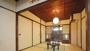 A traditional Japanese room with tatami flooring, sliding doors, and a central tatami mat table with a tea set. - Kyomachiya Shokokuji-an (Kyoto)