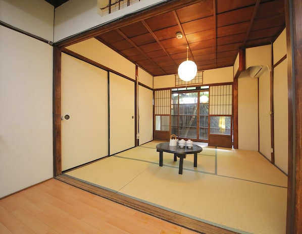 Una habitación japonesa tradicional con suelo de tatami, puertas correderas y una mesa central de tatami con un set de té.