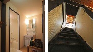 A bathroom with a sink, mirror, and shower. There is a wooden bench with a towel and a basket of toiletries. The bathroom has a tiled floor and walls. - Kyomachiya Shokokuji-an (Kyoto)